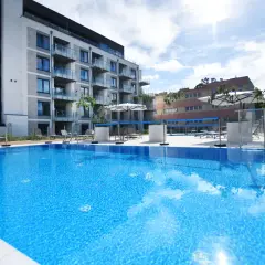 Błękitny basen i nowoczesny budynek z balkonami, idealne miejsce na relaks. Travelist Kołobrzeg zaprasza!