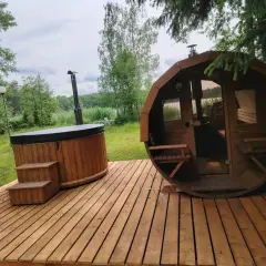 Drewniany domek z jacuzzi i sauną na wyłączność, otoczony zielenią, z widokiem na jezioro. Idealne miejsce na relaks.