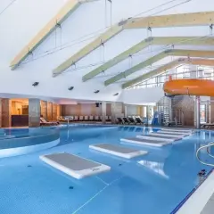 Wesoła zabawa w hotelu z aquaparkiem: basen, zjeżdżalnie i dmuchane materace czekają na gości.