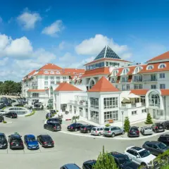 Elegancki hotel 5 gwiazdkowy nad morzem z przestronnym parkingiem pełnym samochodów.