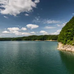 Spokojne jezioro otoczone zielonymi wzgórzami, idealne miejsce na sporty wodne.