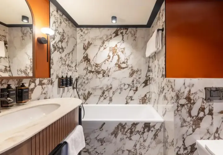 Elegancka łazienka w hotelu Mercure Gdynia z marmurowymi płytkami, wanną i umywalką.