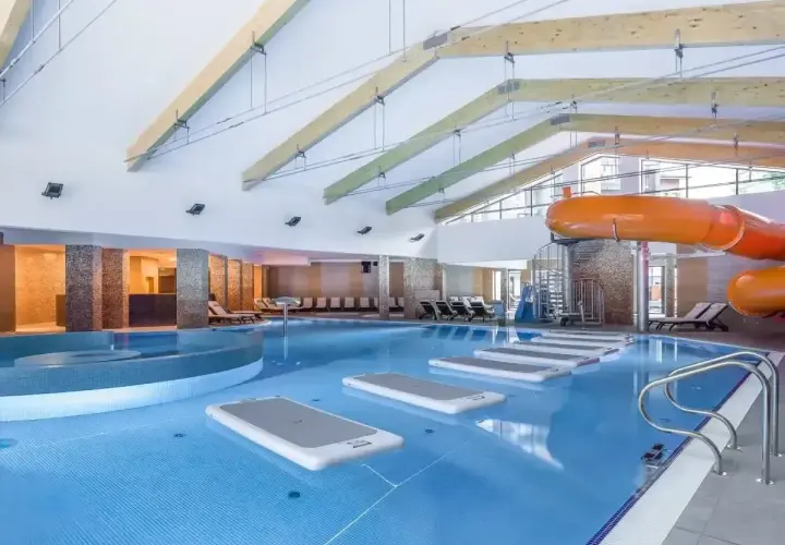 Wesoła zabawa w hotelu z aquaparkiem: basen, zjeżdżalnie i dmuchane materace czekają na gości.