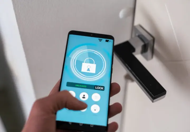 Smartfon z aplikacją do zarządzania domem. Widoczny przycisk "LOCK" i ikona kłódki. Ułatwia to check in.