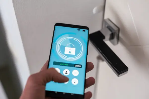 Smartfon z aplikacją do zarządzania domem. Widoczny przycisk "LOCK" i ikona kłódki. Ułatwia to check in.